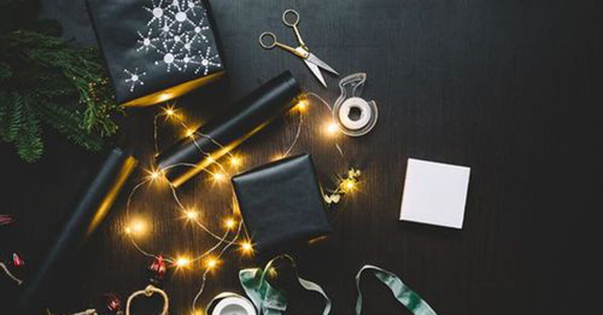 Wrapping paper on a table with fairly lights, tape and scissors  