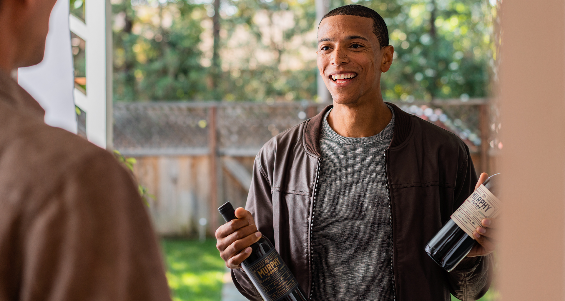 Young Man at the door holding two bottles of Murphy-Goode Wines