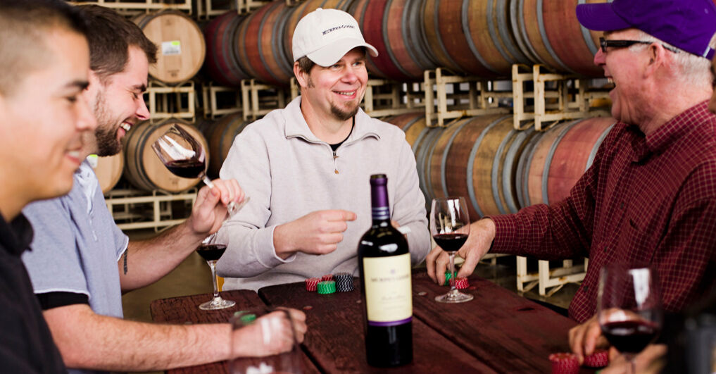 Folks sitting around a table with wine and poker chips