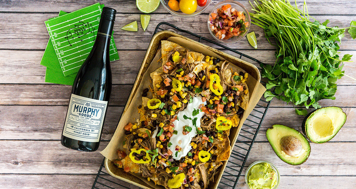 Gameday pulled pork nachos on a table with a bottle of Murphy-Goode Wine