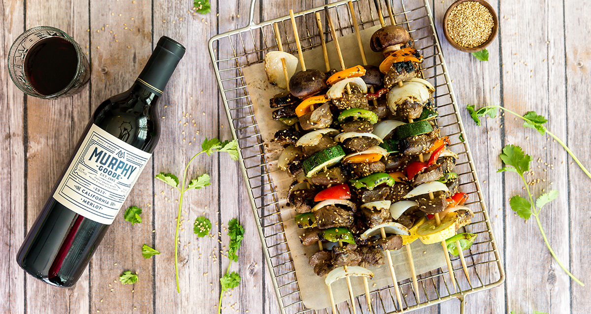 Korean Beef Skewers on a table with a bottle of Murphy-Goode Wine
