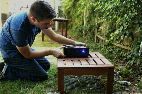 Man setting up projector in a backyard