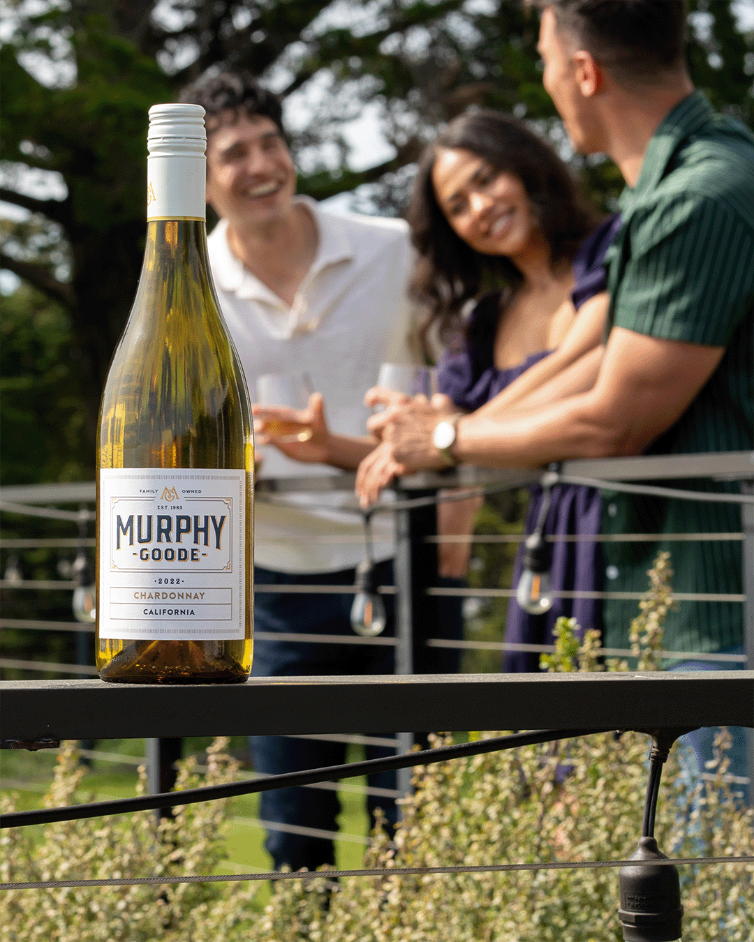 Woman and men friends enjoying their outdoor patio and drinking glasses of white wine from Murphy-Goode Chardonnay bottle
