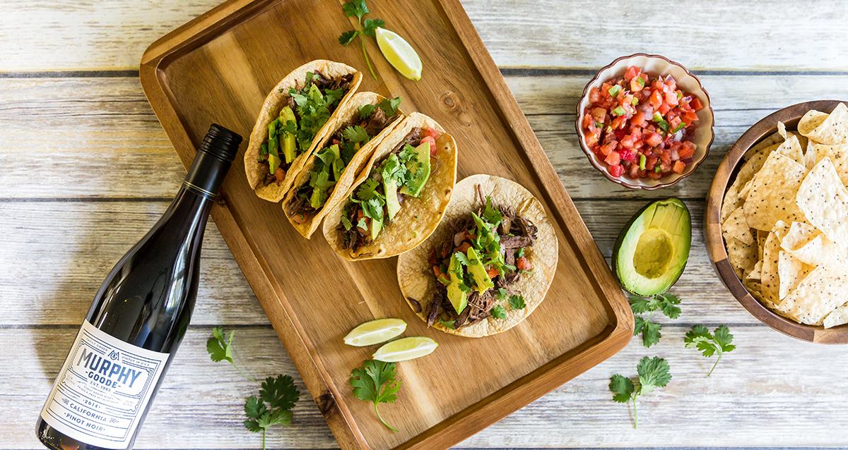 Carnitas tacos with a bottle on a table 