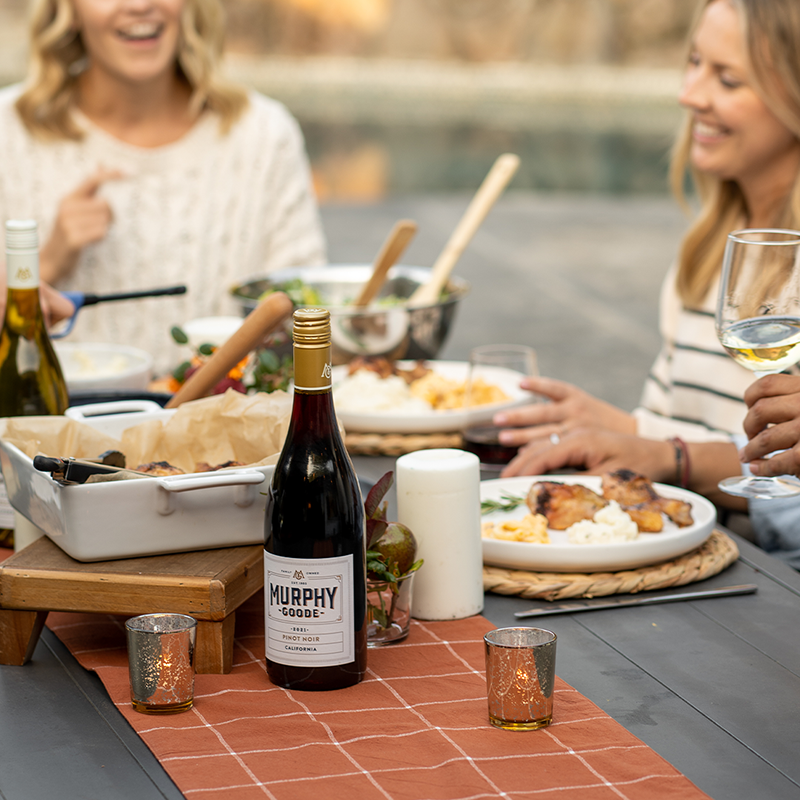 An open bottle of Murphy Goode California Pinot Noir on a table with people in the background.