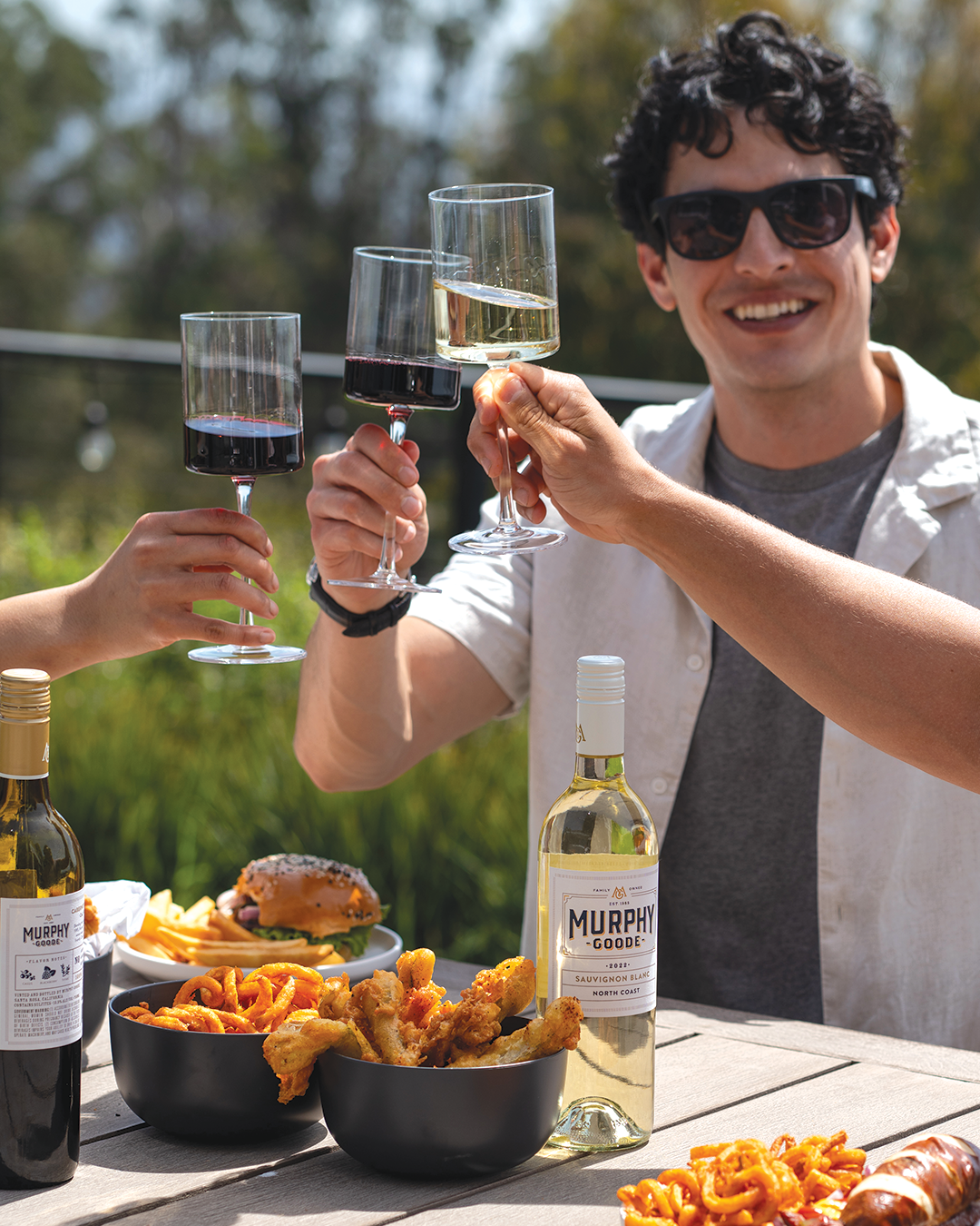 Glass of red wine and white wine cheerings by friends at a outdoor table on a patio